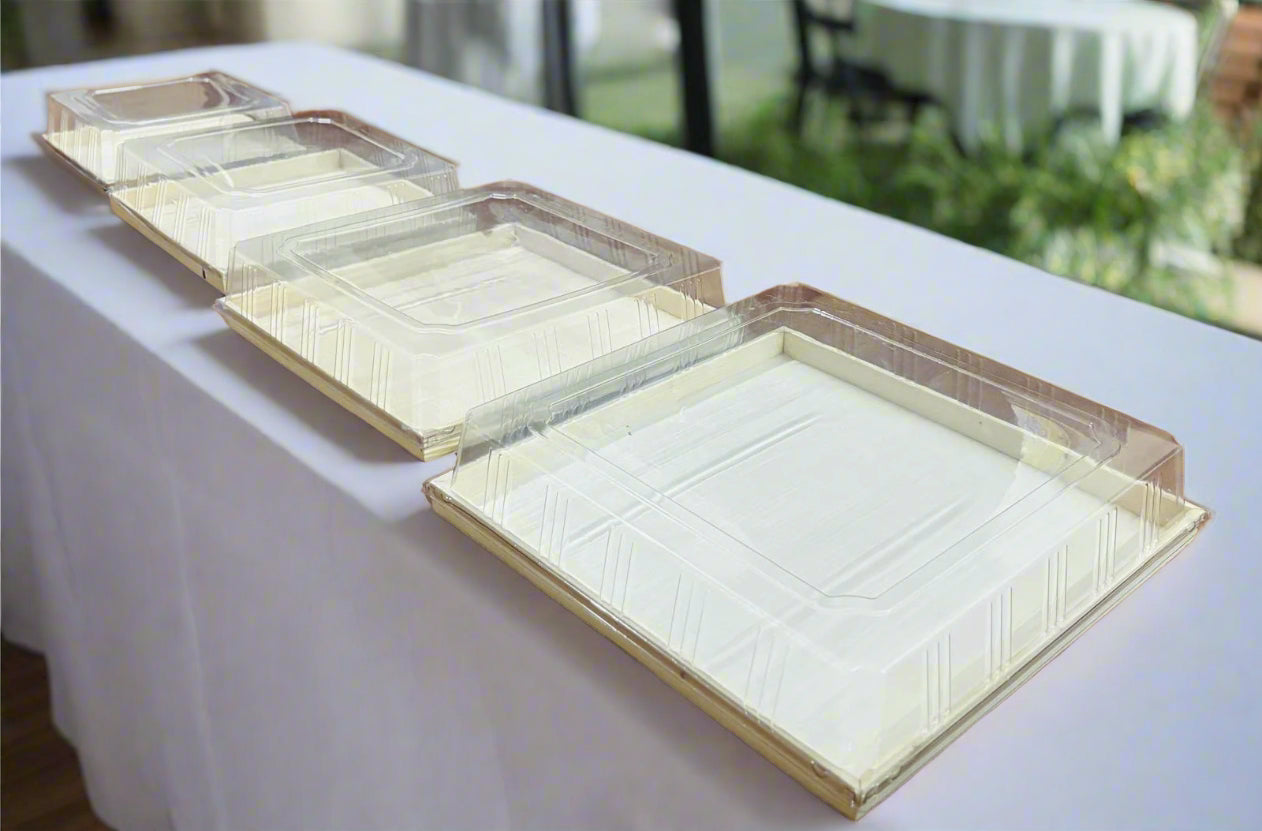 Set of clear plastic trays on a white tablecloth with a blurred outdoor background