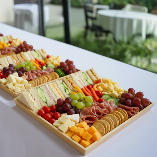 Plated arrangement of sandwiches, fruits, and meats in wooden trays
