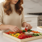 Woman preparing vegetables on a cutting board in a kitchen

